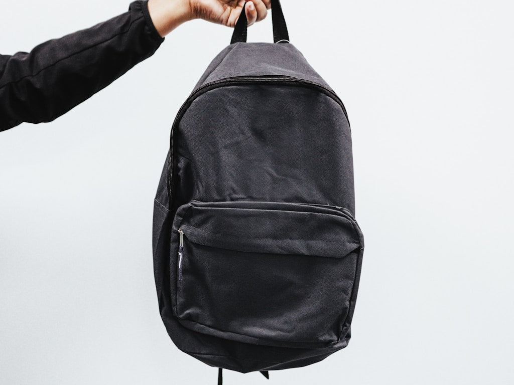 Leather backpack on a wooden desk next to a fabric backpack for comparison