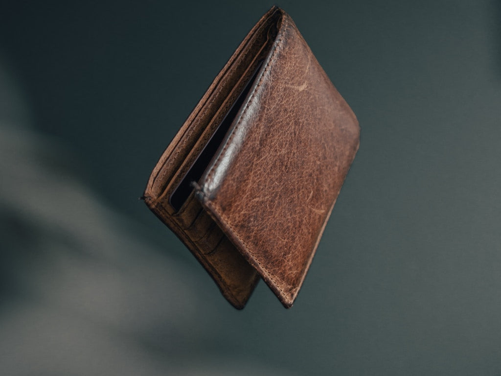 Slim full-grain leather wallet on a wooden surface showing card slots and natural texture
