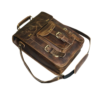 This Image Displays A Vintage-style Sling Leather Bag LaThis Imageid At An Angle, Highlighting Its Rich Craftsmanship And Sturdy Build. Made From Dark Brown Buffalo Leather, The Bag Features Natural Grain Patterns And A Rugged Finish That Adds To Its Timeless Appeal. The Front Flap Is Secured With Dual Buckle Straps, While A Smaller Pocket Below Provides Additional Storage With Its Own Buckle Closure. Brass-polished Hardware Enhances Both The Durability And Classic Aesthetic Of The Bag. A Strong Top Handle
