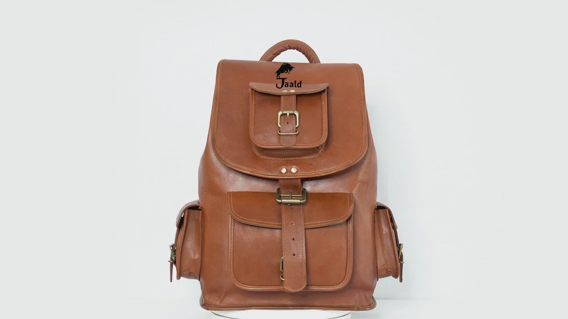 Crafted From Rich, Full-grain Tan Leather, This Vintage-style Rucksack By Jaald Is A Perfect Personalized Or Customized Gift For Men And Women. With Spacious Main Compartment Flap Buckle Closure, It Offers Secure Storage Classic Charm. Front Side Pockets Brass Buckles Allow Easy Access To Essentials, While The Sturdy Top Handle Padded Shoulder Straps Ensure Comfort. Timeless Graduation Gift, Birthday Travel Companion Blending Durability Old-world Elegance.